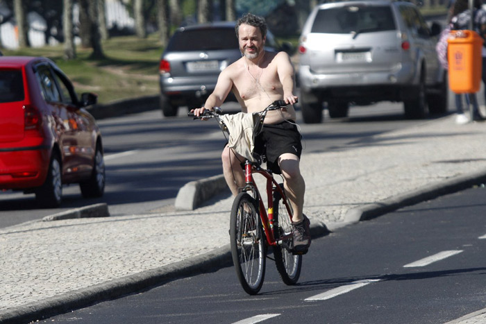 Sem camisa, Leonardo Medeiros pedala pela orla da Barra da Tijuca, no Rio