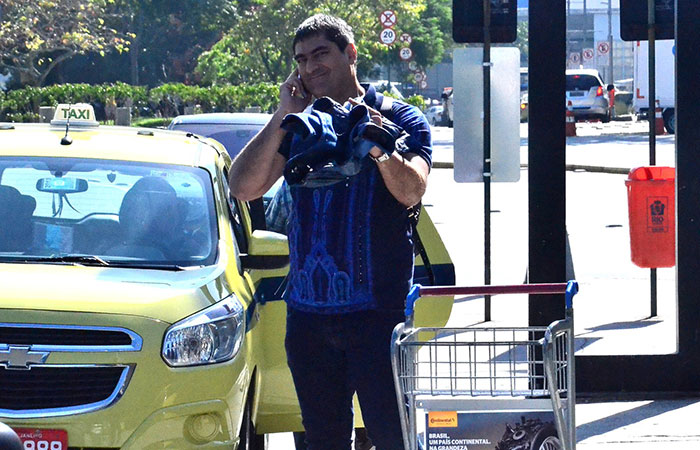 Falando ao celular, Zeca Camargo desembarca no Rio de Janeiro