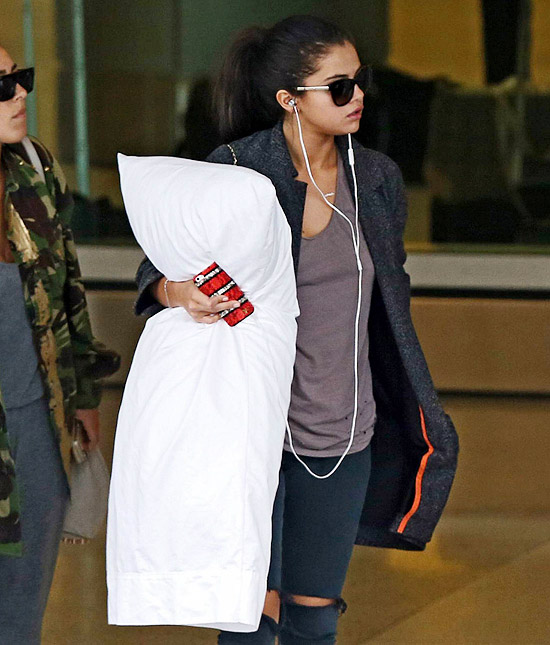 Selena Gomez viaja abraçada a travesseiro gigante