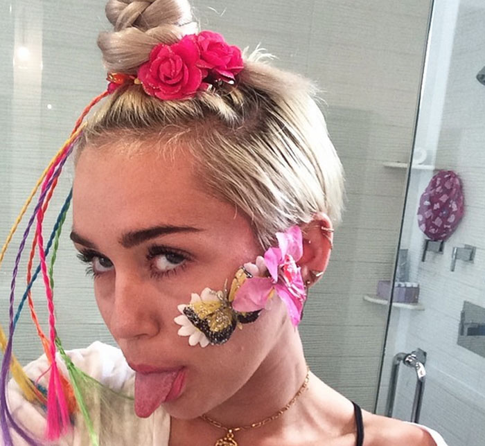 Miley Cyrus esconde espinha no rosto com acessórios coloridos