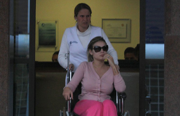 Andressa Urach deixa hospital em cadeira de rodas