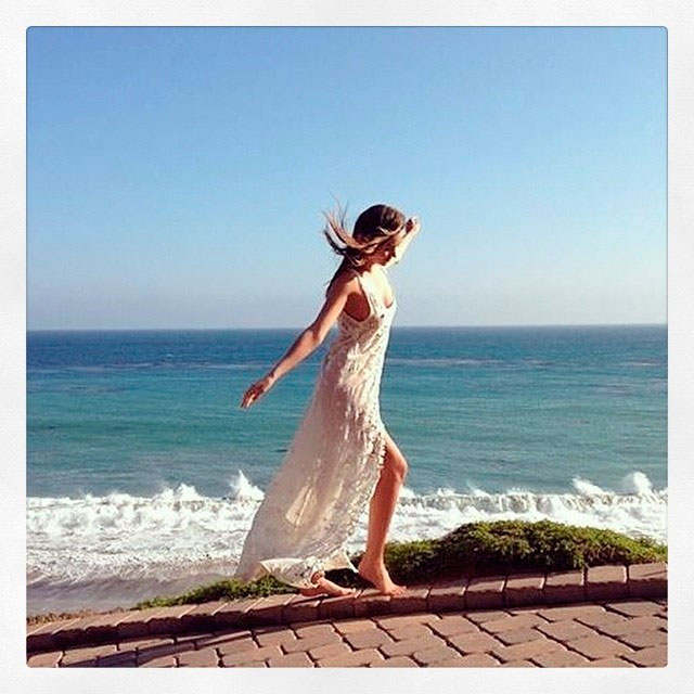 Miranda Kerr posa com vestido longa com praia paradisíaca de fundo