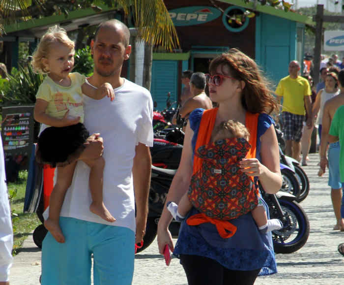 Carolinie Figueiredo passeia com a família e amamenta o pequeno Theo na orla da praia