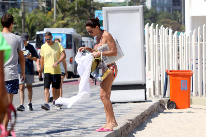 Carolina Ferraz lê jornal em tarde de praia com o namorado