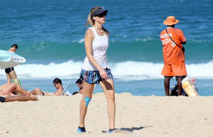  De viseira e óculos escuros, Luana Piovani se exercita nas areias de praia carioca