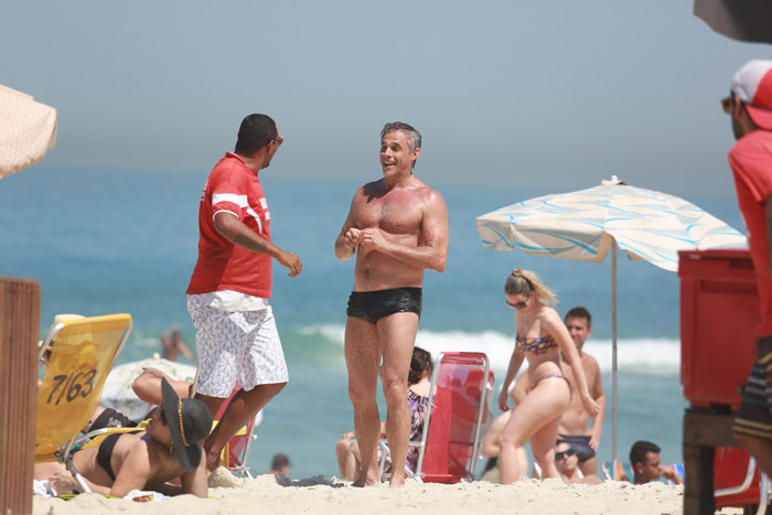 Oscar Magrini cai no riso com fã na praia da Barra