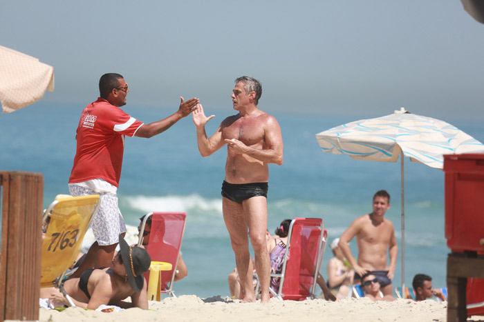 Oscar Magrini cai no riso com fã na praia da Barra