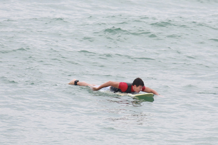 Rodrigo Faro se esforça para tentar pegar onda na praia da Macumba, no Rio 