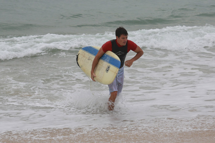 Rodrigo Faro se esforça para tentar pegar onda na praia da Macumba, no Rio 