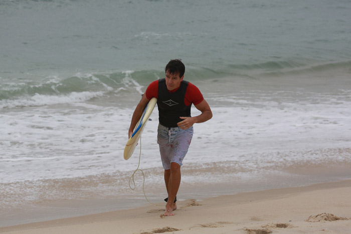 Rodrigo Faro se esforça para tentar pegar onda na praia da Macumba, no Rio 