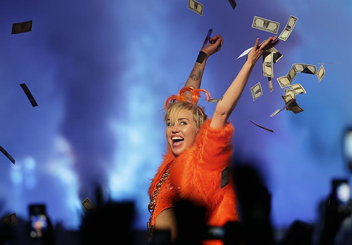 Miley Cyrus faz poses abusadas e joga dinheiro pro alto durante show 