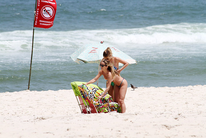 Danielle Winits pega praia e aproveita o mar de biquininho fio-dental