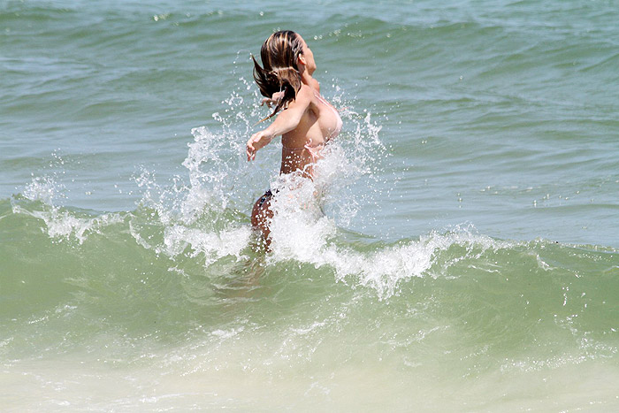 Danielle Winits pega praia e aproveita o mar de biquininho fio-dental
