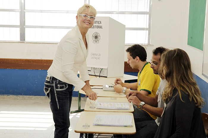 De bota ortopédica, Xuxa abre o sorrisão depois de registrar seu voto,