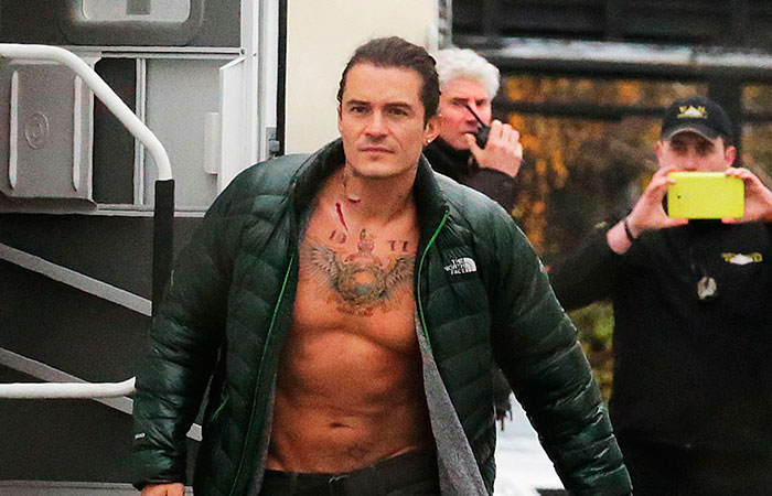 Orlando Bloom exibe tatuagem no peito durante filmagem