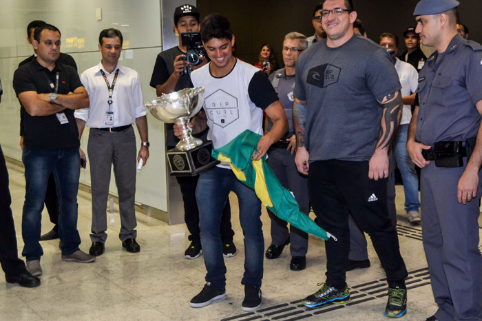 Gabriel Medina chega ao Brasil com bandeira do país e troféu na mão