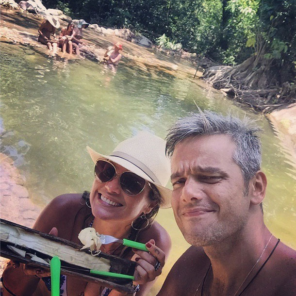 Flávia Alessandra aparece sorridente ao lado do marido curtindo uma comidinha natural nas férias