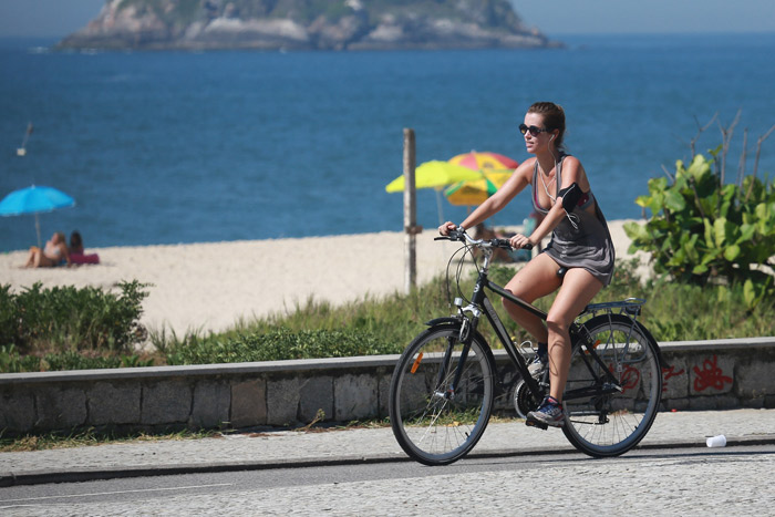 De vestido, Juliana Didone anda de bicicleta na praia da Macumba