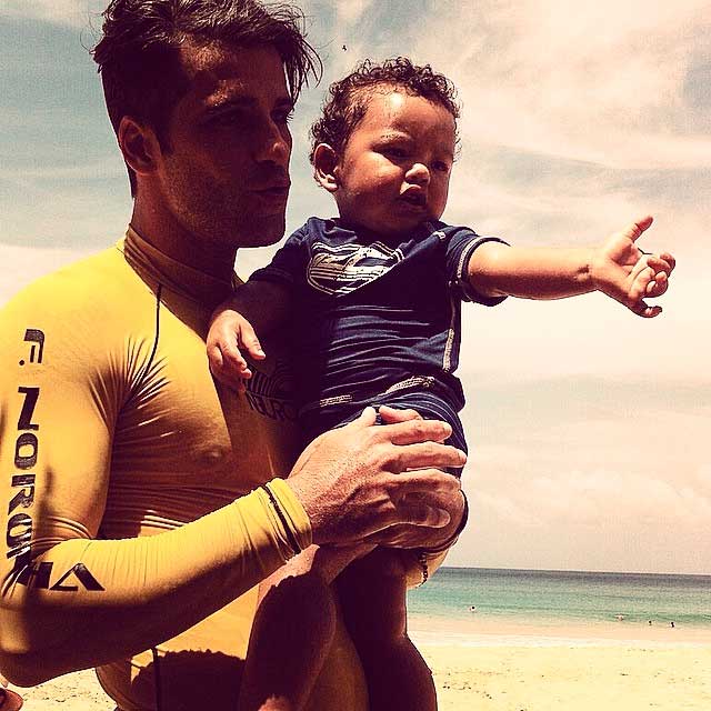 Bruno Gagliasso mima o afilhado ainda com roupa de surfe na praia