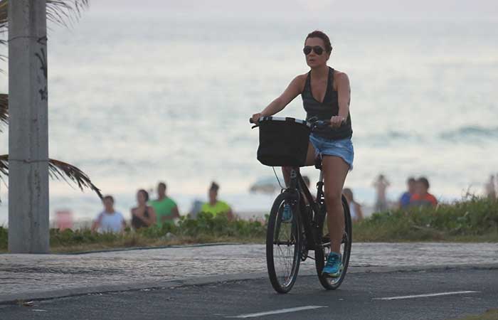 Sem maquiagem e de shortinho, Adriana Esteves pedala na orla da praia da Barra da Tijuca