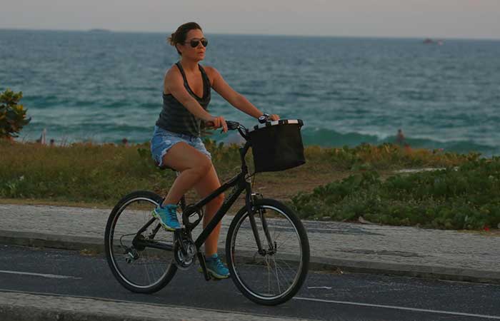 Sem maquiagem e de shortinho, Adriana Esteves pedala na orla da praia da Barra da Tijuca