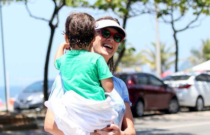 Toda molhada, Letícia Birkheuer carrega o filho depois de se refrescar na praia