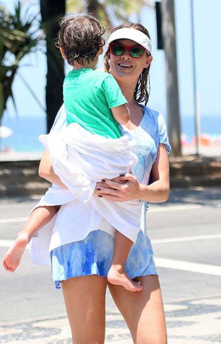 Toda molhada, Letícia Birkheuer carrega o filho depois de se refrescar na praia