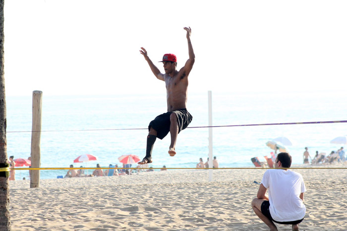 De boné, Marcello Melo Jr. pratica slackline em praia do Rio de Janeiro