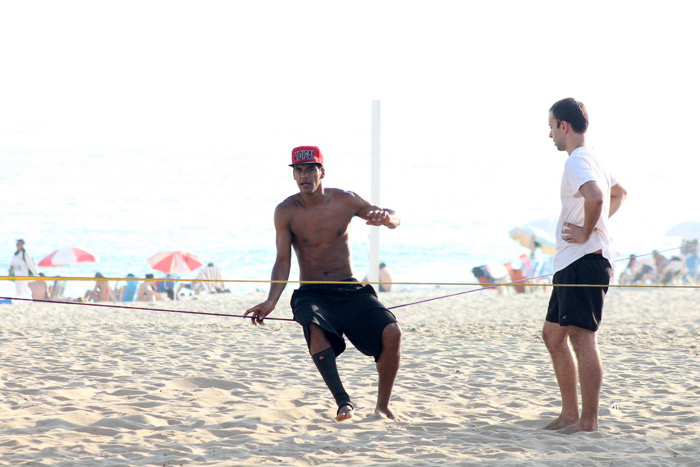 De boné, Marcello Melo Jr. pratica slackline em praia do Rio de Janeiro