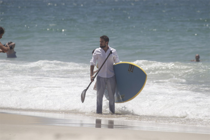 Rafael Cardoso pratica stand up paddle de roupa e tudo em praia carioca