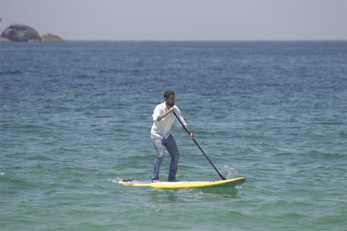 Rafael Cardoso pratica stand up paddle de roupa e tudo em praia carioca