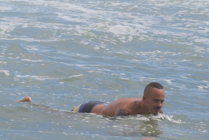 Paulo Vilhena se refresca do calor surfando no mar carioca