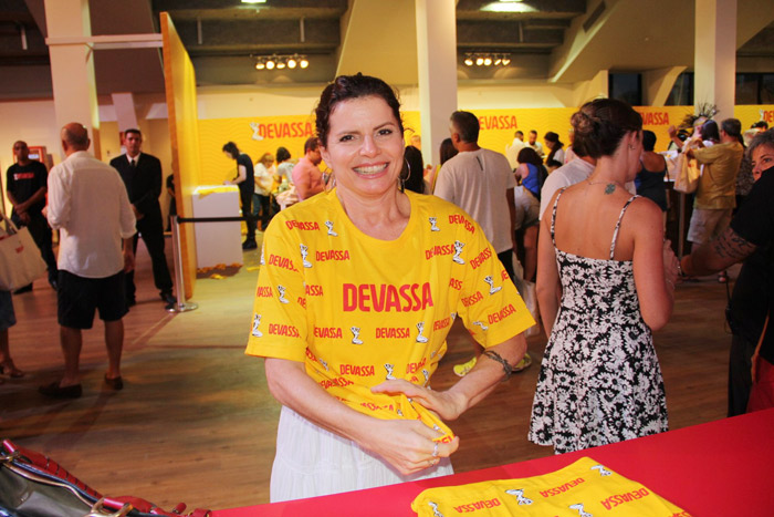 Débora Bloch, toda sorridente, experimentando camiseta para curtir o Camarote Devassa 2015