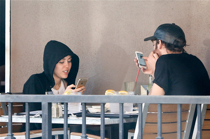 Miley Cyrus não desgruda do celular durante almoço