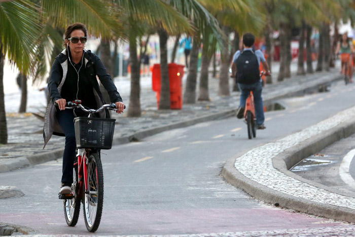 Com look todo preto, Andréa Beltrão passeia de bicicleta pela orla de Ipanema
