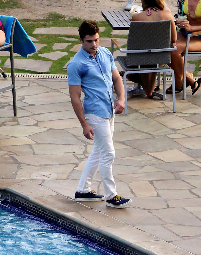 Zac Efron cai na piscina de roupa em filmagem no Havaí