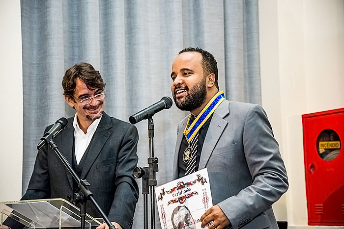 Sacha Rodrigues, neto de Nelson Rodrigues, observa, enquanto Miguel Arcanjo Prado, jornalista e vice-presidente da APCA, agradece a Medalha Nelson Rodrigues