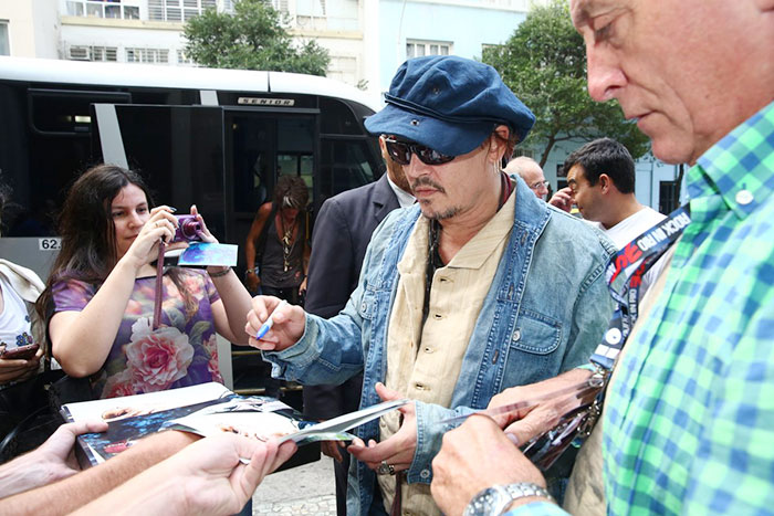 Johnny Depp distribui autógrafos na porta de hotel no Rio