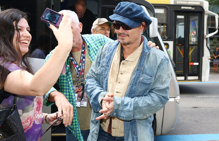 Johnny Depp distribui autógrafos na porta de hotel no Rio
