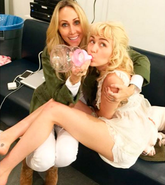 Miley Cyrus posa tomando mamadeira no colo da mãe