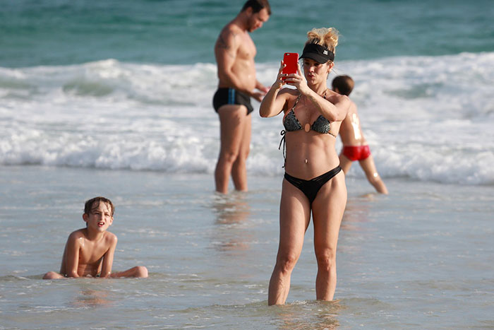Danielle Winits caprichou nas expressões que colocou no rosto para fazer selfies na praia, e foi observada pelo primogênito, Noah