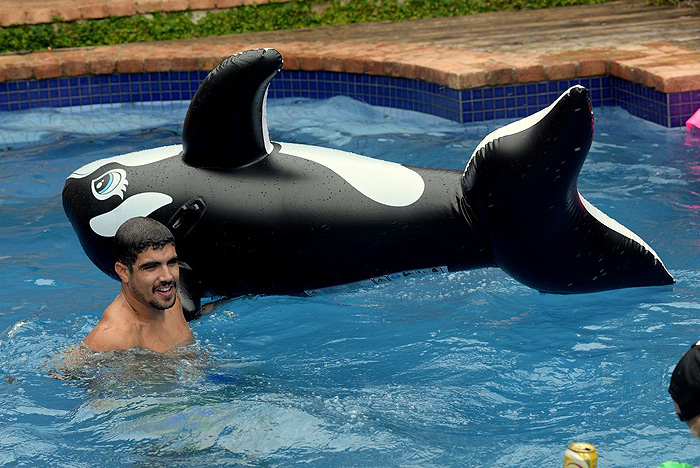 Querendo aproveitar a água para brincar, ele decidiu pegar um acessório em formato de baleia, que usou para ir de uma borda até a outra