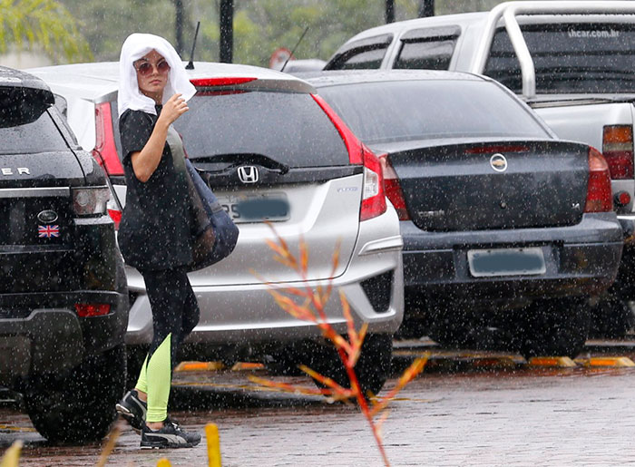 Na chuva, Isis Valverde protege o cabelo com uma toalha
