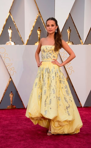 A atriz sueca Alicia Vikander escolheu um tomara que caia amarelo suave.