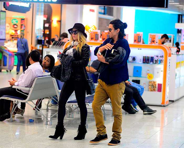 Dani Winits e André Gonçalves circulam por aeroporto no Rio