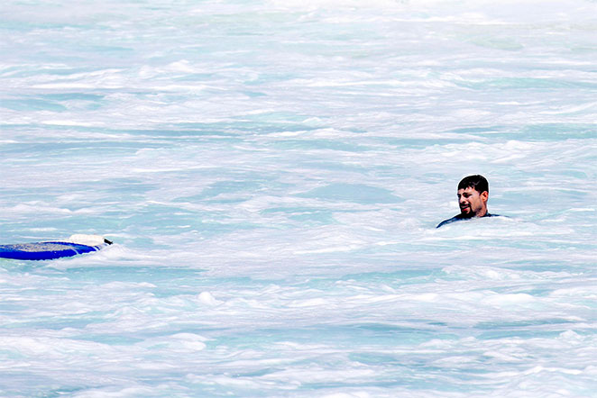 Cauã Reymond acena para fotógrafo após curtir o mar carioca