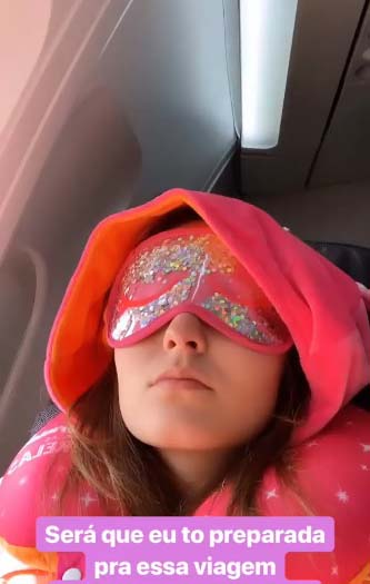 Larissa Manoela com a máscara e a almofada de pescoço antes de decolar