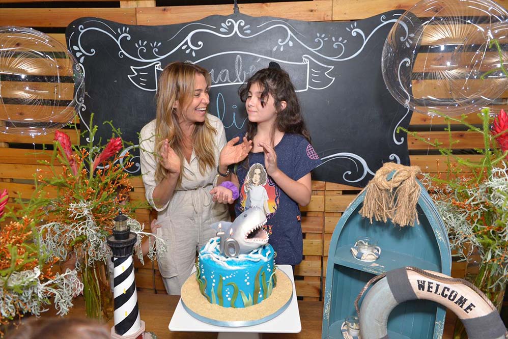 Mônica Martelli com a filha, Julia, e o cenário inspirado no mar. Rolou até um bolo com tubarão no topo