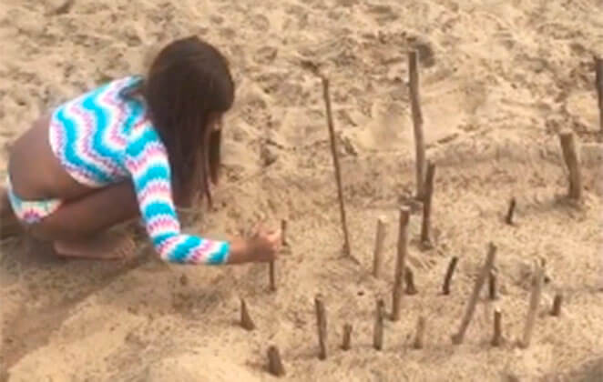 Sofia brinca de fazer castelinhos de areia na praia