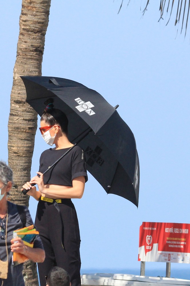 Camila Queiroz se protegeu do sol embaixo de um guarda-sol